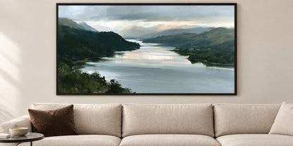 a large, framed painting of a serene landscape depicting a calm river surrounded by mountains and lush greenery.